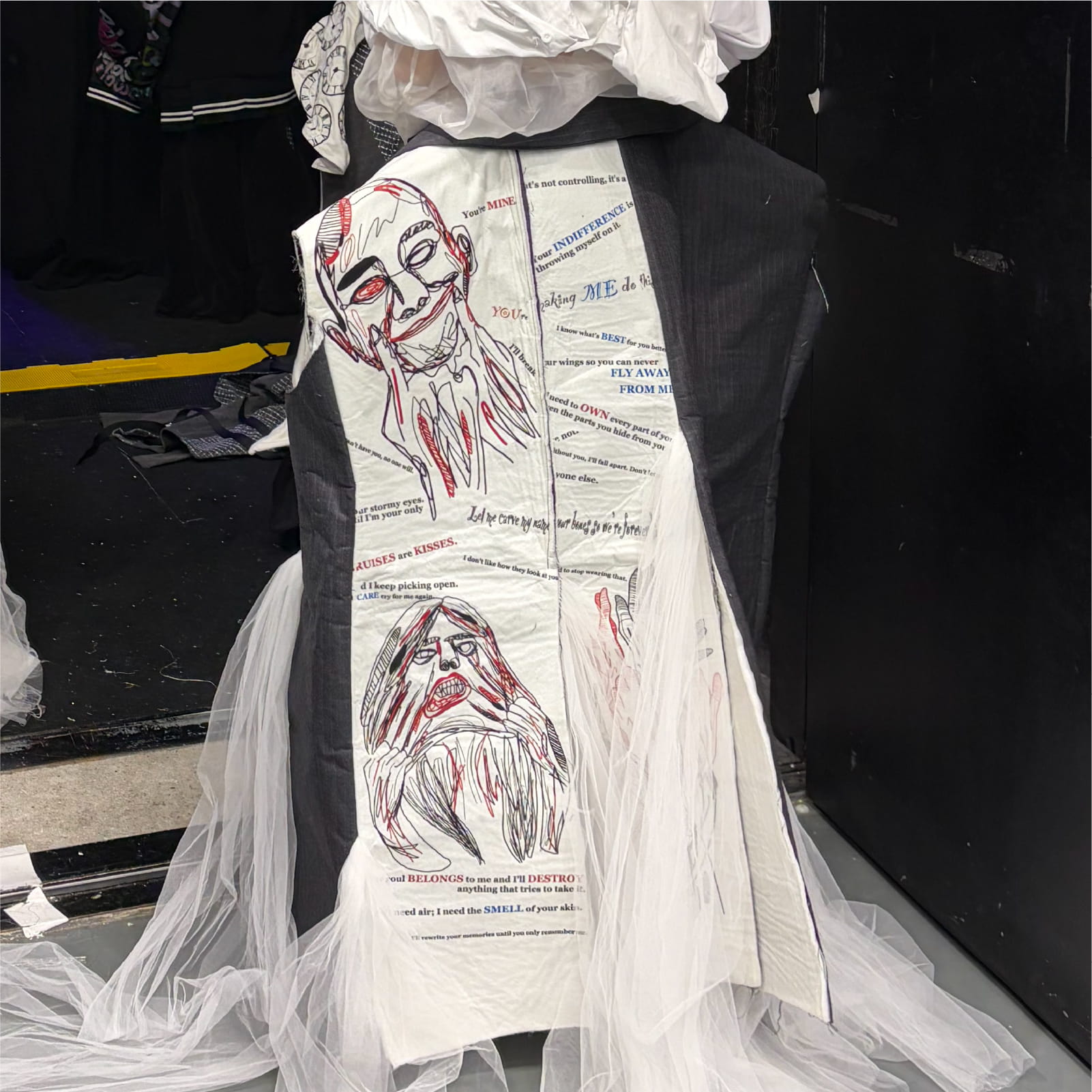 Close-up of the complex embroidery details on a garment from the "PATHOLOGICAL LOVE" collection, featuring stitched faces and text like "You're MINE" created using a Brother commercial embroidery machine.
