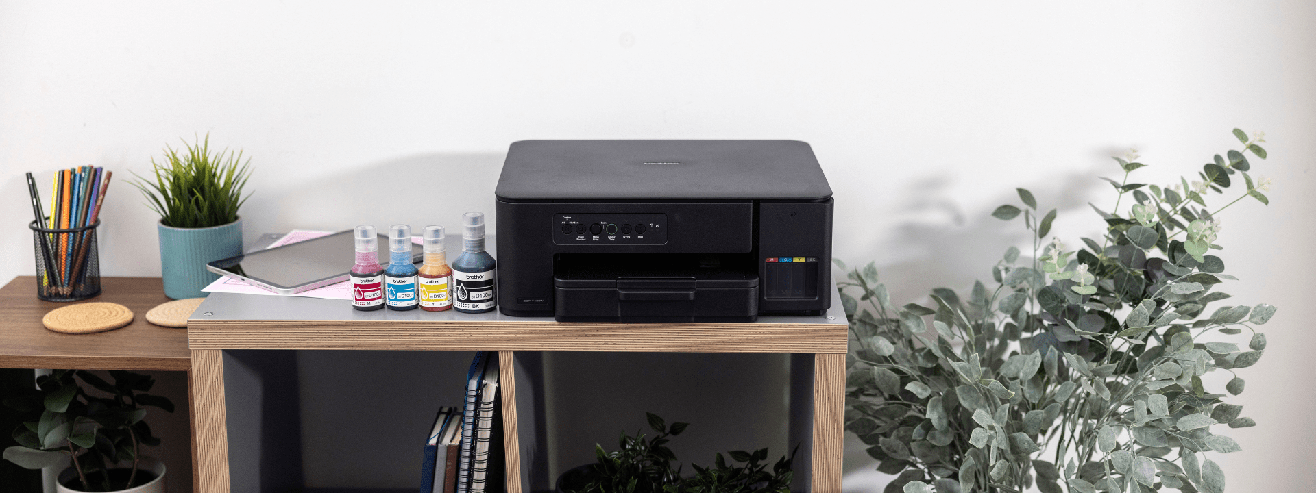 A compact printer positioned on a shelf alongside two plants, balancing technology and natural elements in the office.